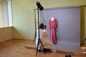 Frau in weißem Mantel beim Fotografieren eines Kleidungsstückes