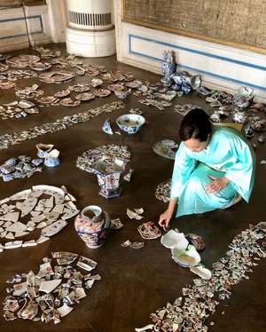 Japanische Frau setzt Porzellanscherben zusammen