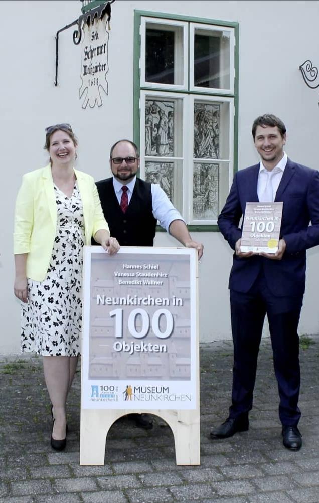 Vanessa Staudenhirz, Hannes Schiel und Benedikt Wallner vor einem Plakat zum Buch "Neunkirchen in 1000 Objekten"